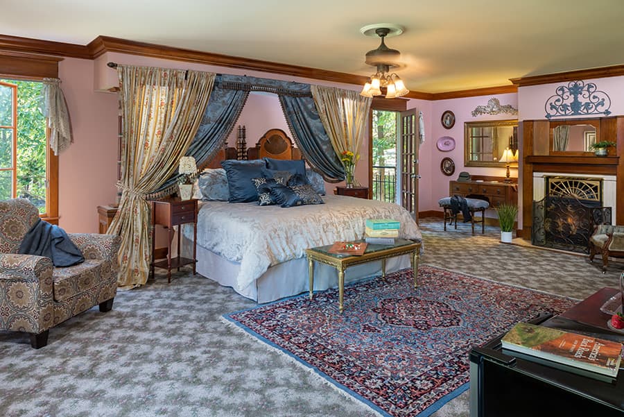 Spacious, elegantly decorated bedroom with a large bed, cozy seating area, and natural light from windows.