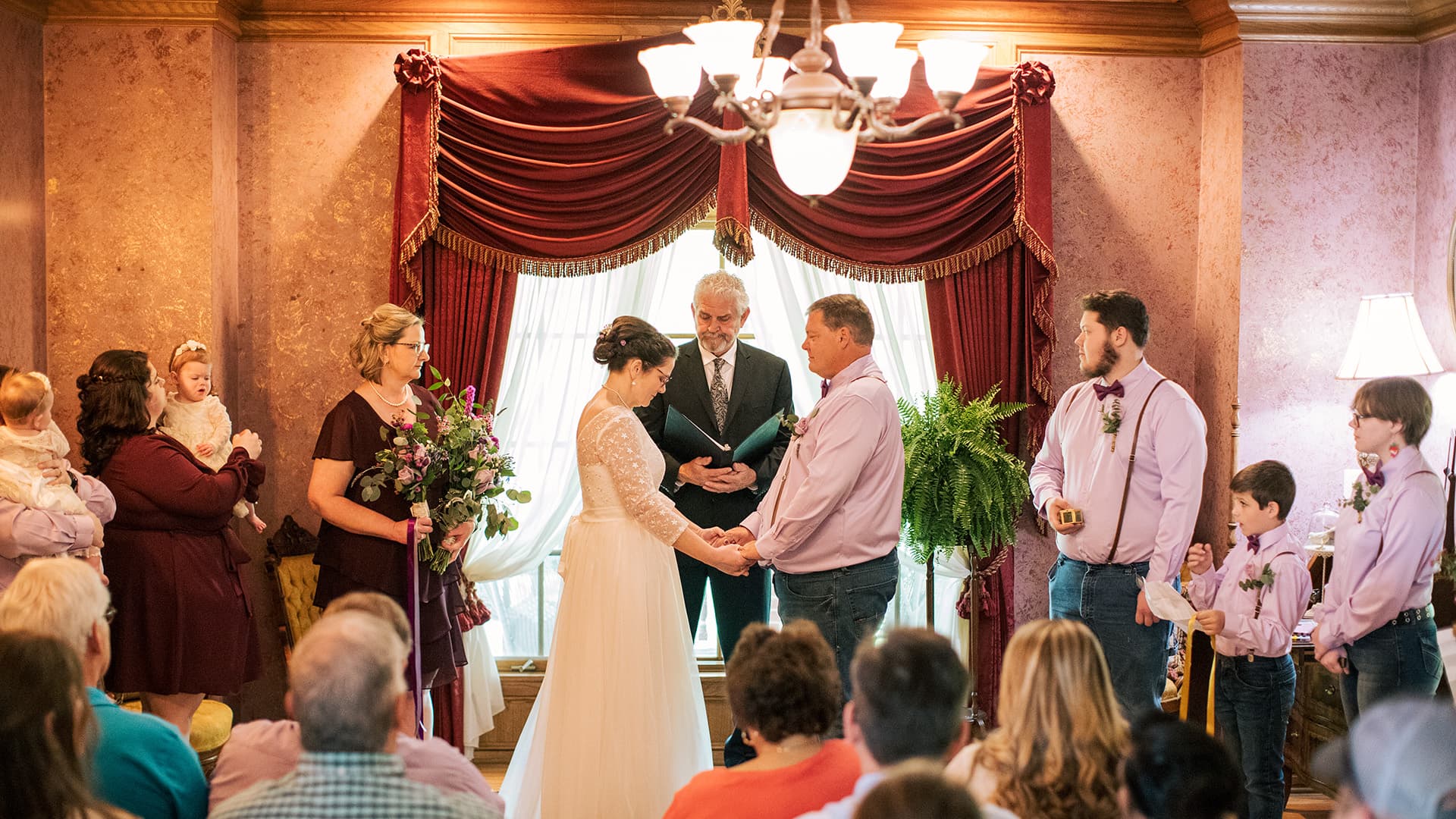 A couple exchanges vows during a wedding ceremony surrounded by family and friends.