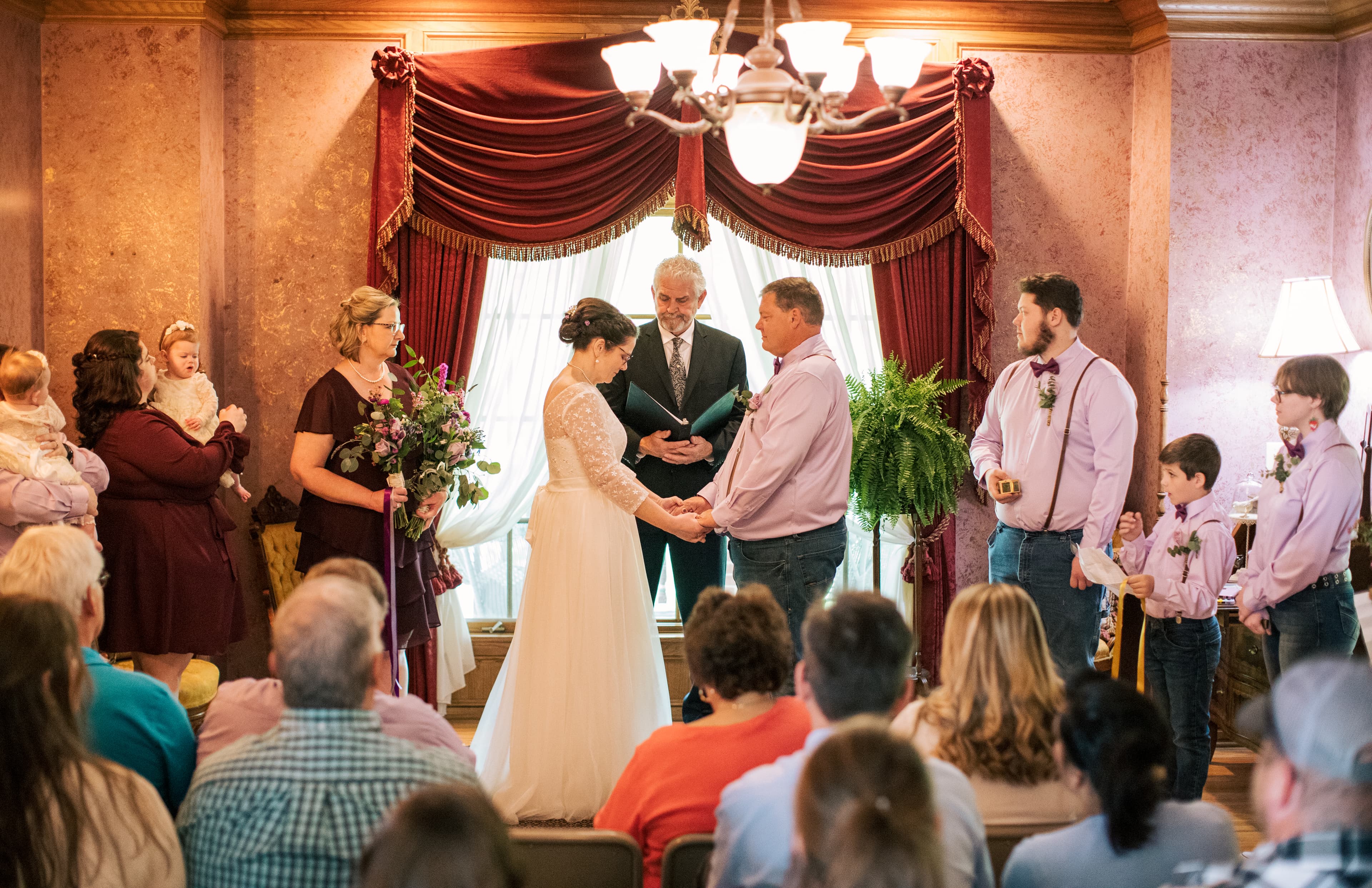 A couple exchanges vows during a wedding ceremony surrounded by family and friends.
