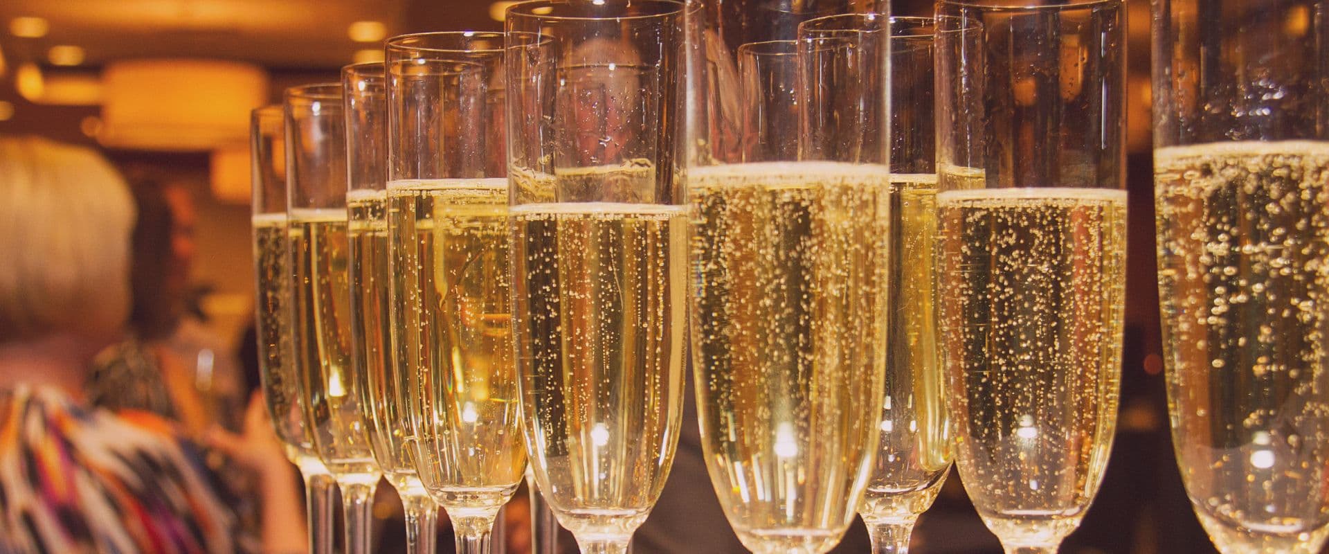 A row of champagne flutes filled with bubbly liquid.