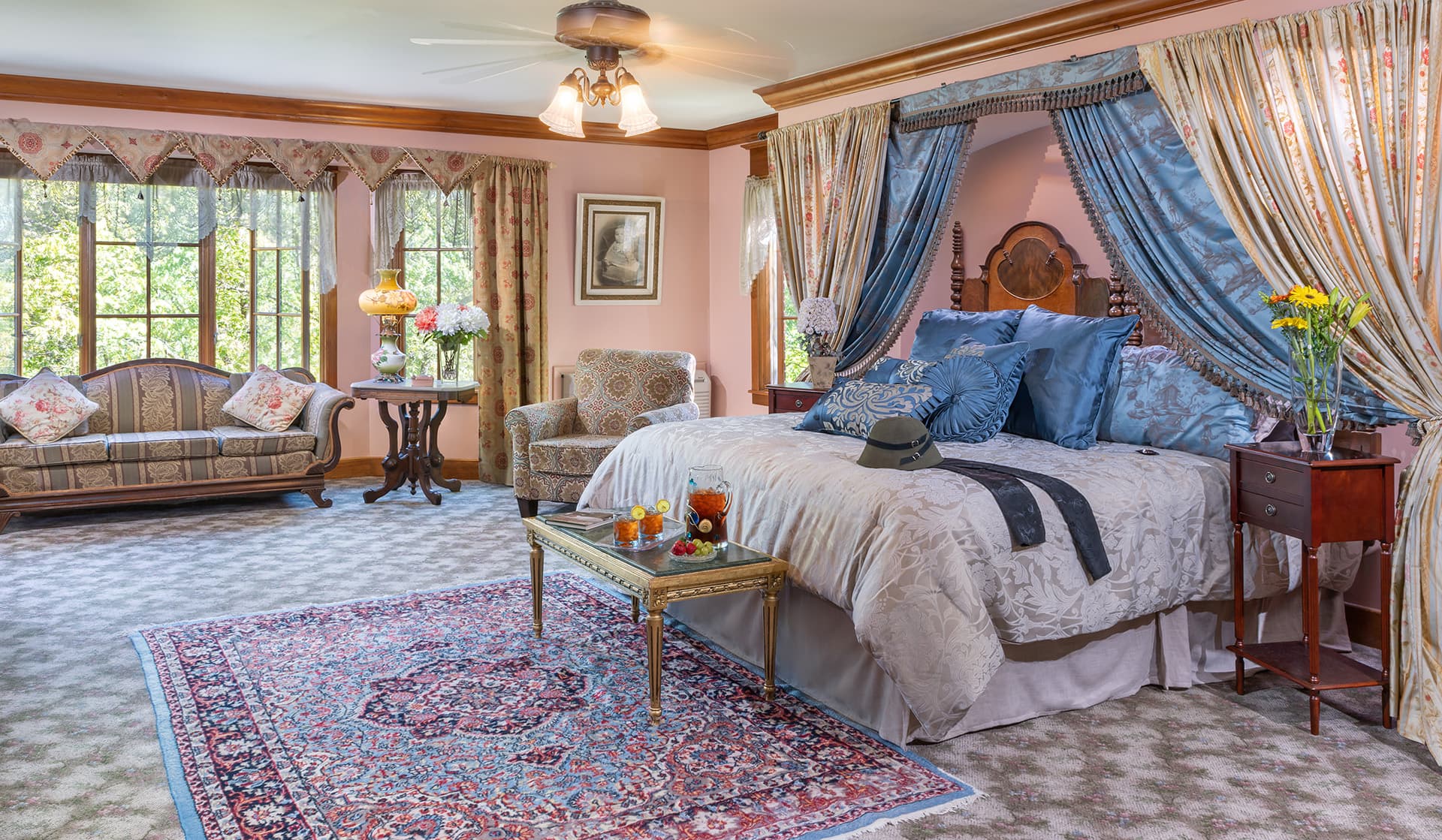 A cozy bedroom featuring a large bed with decorative pillows, elegant curtains, and a comfortable seating area.