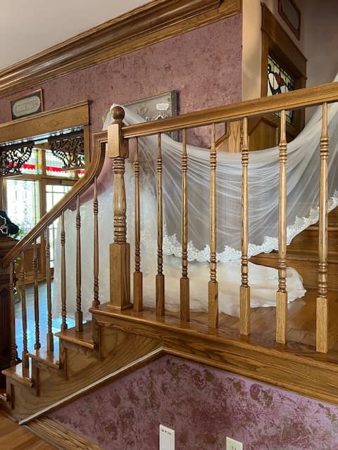 A sheer white fabric drapes elegantly over a wooden staircase with ornate railings.