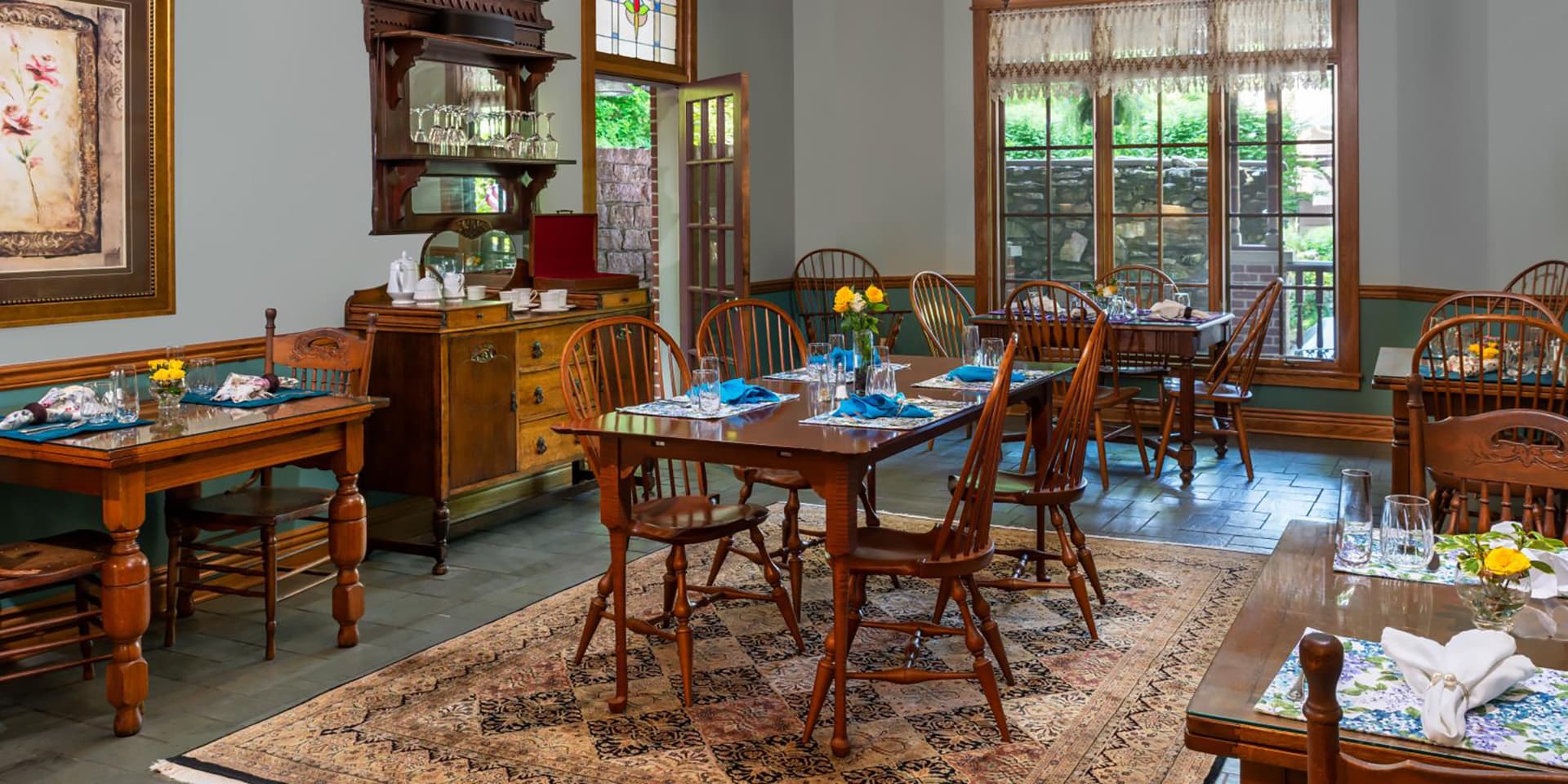 A cozy dining room with wooden tables, chairs, and floral decor.